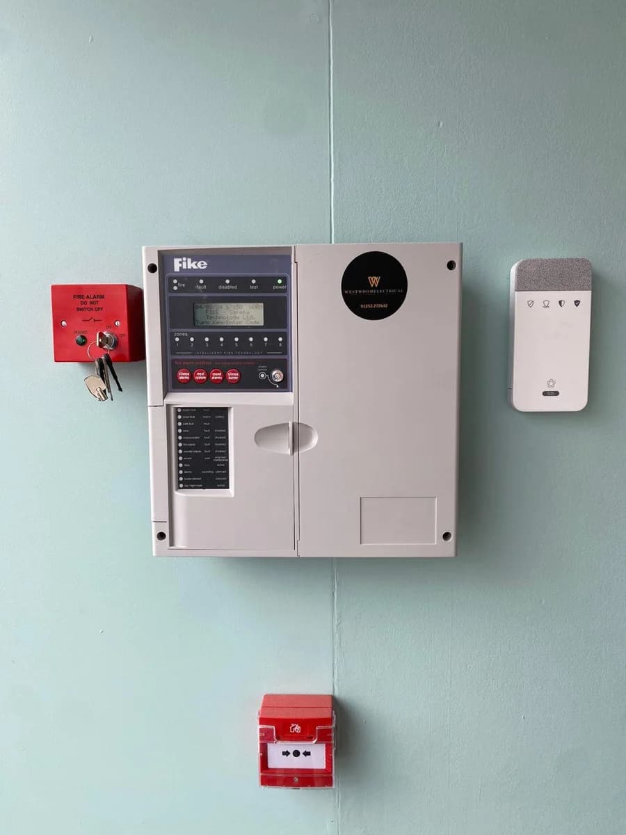 Fire alarm panel and call point mounted on a wall